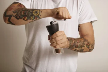 Man grinding coffee beans with a manual coffee grinder