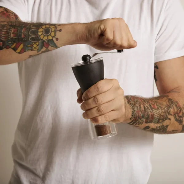 Man grinding coffee beans with a manual coffee grinder