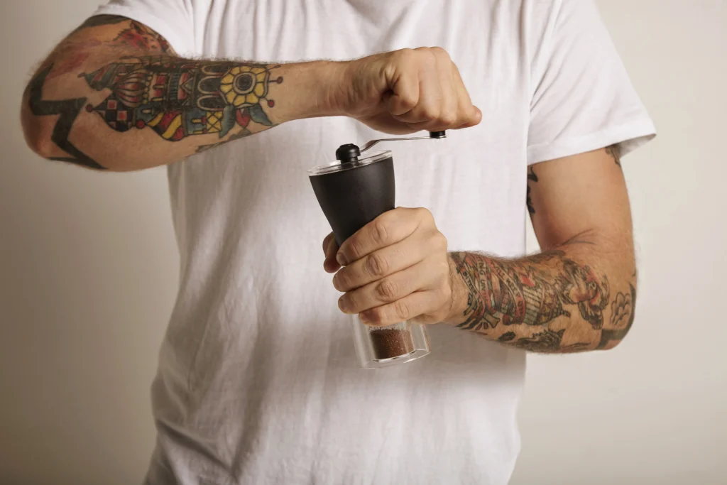 Man grinding coffee beans with a manual coffee grinder