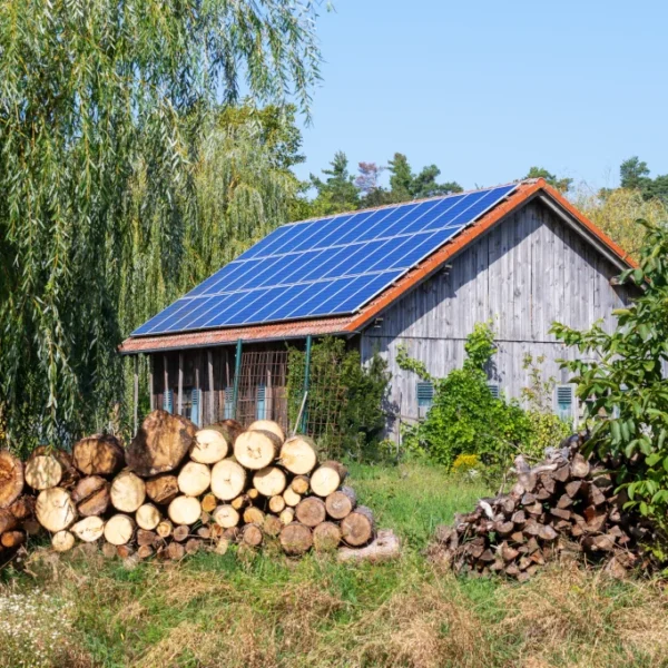 Wooden cabin with solar panels on the roof and stacked firewood