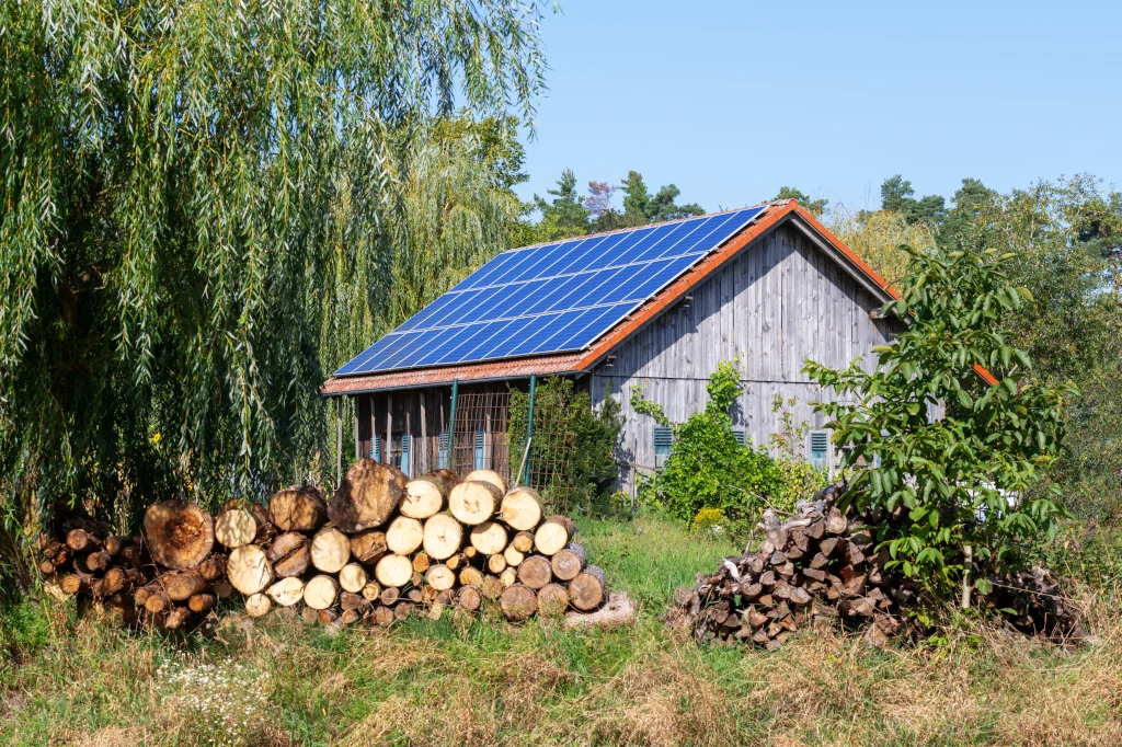 Wooden cabin with solar panels on the roof and stacked firewood