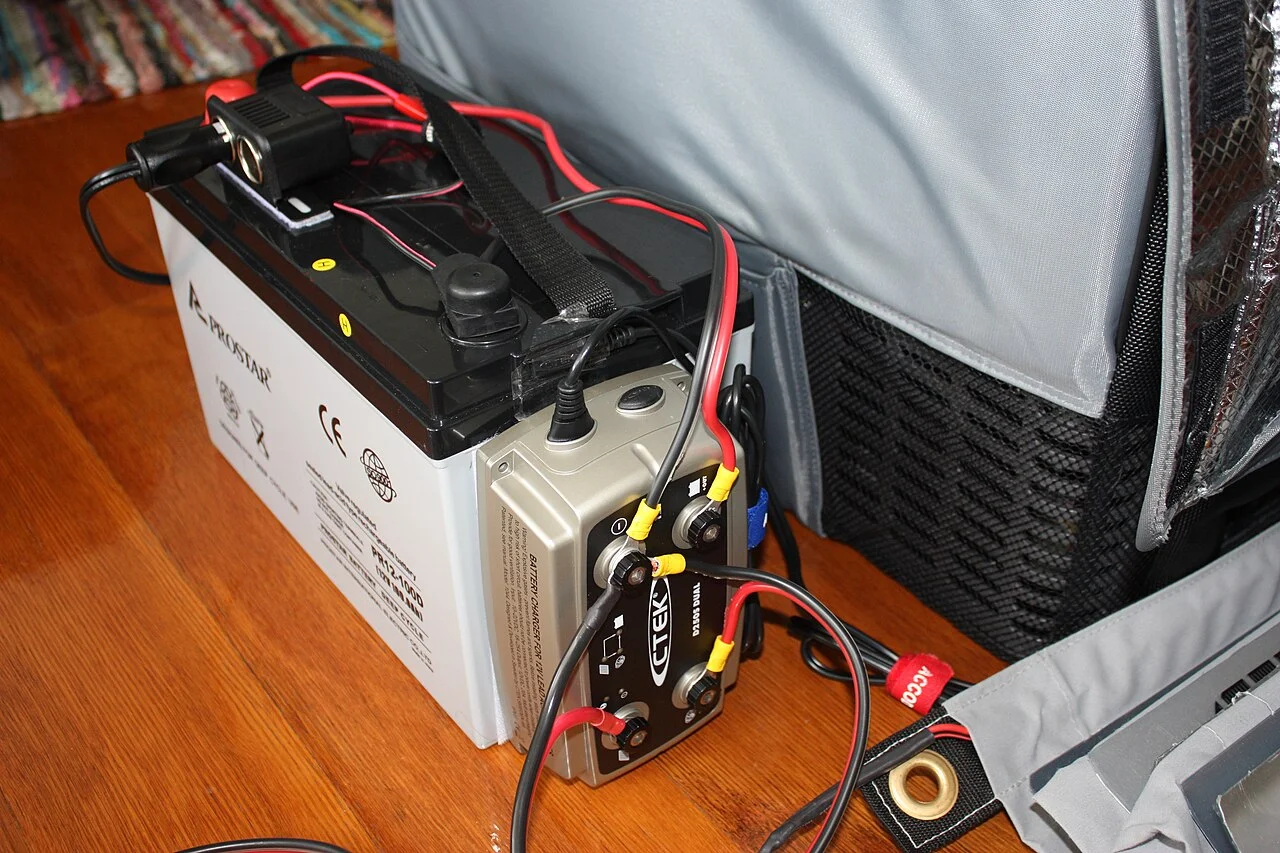 A deep-cycle auxiliary battery with a charger, set up as the house battery for a power inverter